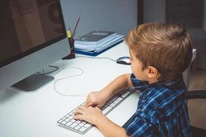 Small kid working on desktop computer. photo