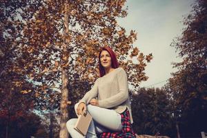Beautiful redhead woman daydreaming in the park. photo