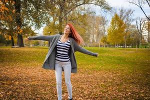 Beautiful woman enjoying in autumn with park with arms outstretched. photo
