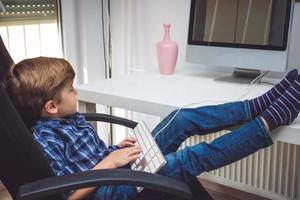 Relaxed kid surfing the internet on computer at home. photo