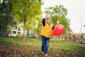 niño juguetón divirtiéndose con globo en el parque. foto