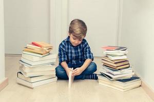 Little boy reading among stack of books. photo