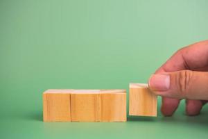 hand holding cube wood block blank on green background. copy space photo