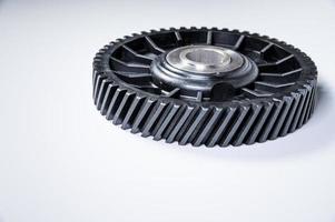 Black polymer gear camshaft with metal base. New spare part for an internal combustion engine on a gray background photo