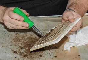 Cleaning a very dirty kitchen exhaust fan from dirt with a brush. A man cleans the parts of a fan with a brush photo