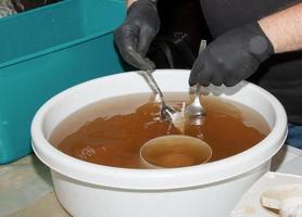 Washing the plastic parts of a very dirty kitchen exhaust fan in an aqueous solution of sodium hydroxide. A man works in protective gloves. photo