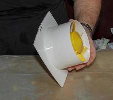 The process of assembling the kitchen exhaust fan after cleaning the wash. A man works with a screwdriver in his hands photo
