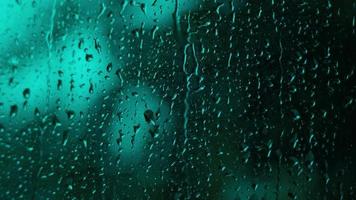gotas de lluvia en el cristal. pequeña gota de lluvia descansa sobre el vidrio mientras llueve. video