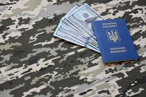 SUMY, UKRAINE - MARCH 20, 2022 Ukrainian foreign passport on fabric with texture of military pixeled camouflage. Cloth with camo pattern in grey, brown and green pixel shapes and Ukrainian ID photo