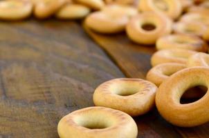 A lot of fresh yellow bagels lie on the surface of the old dark wood. A popular kind of flour products. One of the traditional Russian treats for tea photo