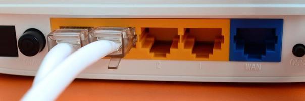 The Internet cable plugs are connected to the Internet router, which lies on a bright orange background. Items required for Internet connection photo