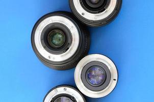 Several photographic lenses lie on a bright blue background. Space for text photo
