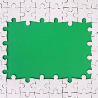 Framing in the form of a rectangle, made of a white jigsaw puzzle around the green space photo