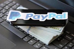 TERNOPIL, UKRAINE - SEPTEMBER 6, 2022 Payoneer paper logotype lies on black laptop with US dollar bills. Payoneer is American financial services company provides online money transfer photo