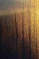 The texture of misted glass with a lot of drops and drips of condensation against the sunlight at dawn. Background image photo