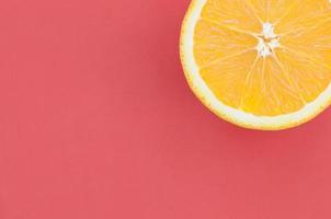 Top view of a one orange fruit slice on bright background in red color. A saturated citrus texture image photo