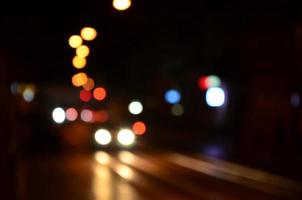 escena nocturna borrosa de tráfico en la carretera. imagen desenfocada de coches que viajan con faros luminosos. arte bokeh foto