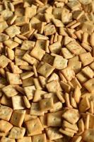 Background texture of small edible squares baked from dough and sprinkled with salt. A lot of salt cracker photo