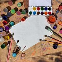 Still life with blank paper, brushes and jars of watercolor and gouache paint photo