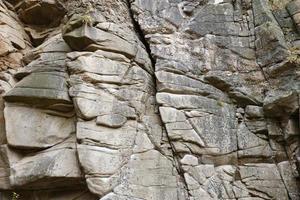 Light coarse natural rock stone background. Mining cliff rough front surface. Big limestone stack backdrop. Heavy grunge damaged granite block texture photo