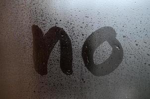 The English word No is written with a finger on the surface of the misted glass photo