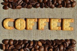 café. la palabra de las letras comestibles se encuentra en el lienzo gris con granos de café foto