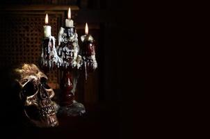 Old battered skull lies with an antique wooden candlestick photo