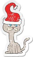 retro distressed sticker of a cartoon cat wearing christmas hat vector