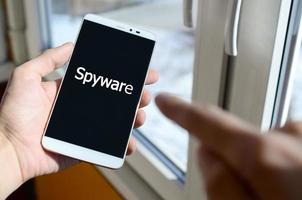 A person sees a white inscription on a black smartphone display that holds in his hand. Spyware photo