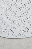 A white jigsaw puzzle in the complete form lies on a treated stone surface. Textured image with copy space photo
