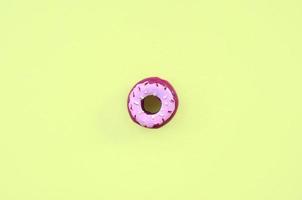 Single small plastic donut lies on a pastel colorful background. Flat lay minimal composition. Top view. photo