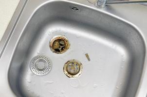 Silvery kitchen sink with a disassembled protective filter during the repair process photo