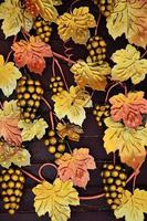 A photograph of forged grapes, painted in warm orange tones on a wooden background. Background image on the topic of winemaking or viticulture photo