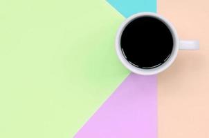 Small white coffee cup on texture background of fashion pastel pink, blue, coral and lime colors paper photo