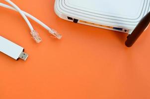 Internet router, portable USB wi-fi adapter and internet cable plugs lie on a bright orange background. Items required for internet connection photo