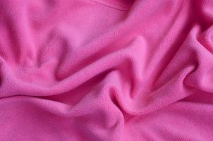The blanket of furry pink fleece fabric. A background of light pink soft plush fleece material with a lot of relief folds photo