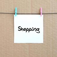 Shopping. Note is written on a white sticker that hangs with a clothespin on a rope on a background of brown cardboard photo