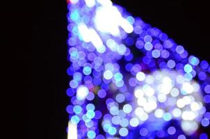 Blurred fragment of the New Year tree. Lots of round lights in blue photo