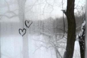 Two hearts painted on a misted glass in winter photo