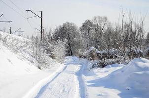 The road that lies parallel to the railway line is covered with snow on a sunny day after a heavy snowfall photo