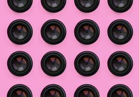 A few camera lenses with a closed aperture lie on texture background of fashion pastel pink color paper in minimal concept. Abstract trendy pattern photo