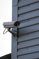 White surveillance camera built into the metal wall of the office building photo