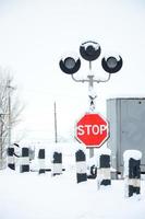 Stop. Red road sign is located on the motorway crossing the railway line in winter season photo