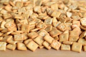 Background texture of small edible squares baked from dough and sprinkled with salt. A lot of salt cracker photo