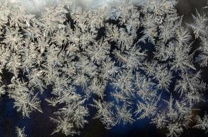 Snowflakes frost rime macro on window glass pane photo