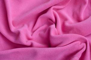 The blanket of furry pink fleece fabric. A background of light pink soft plush fleece material with a lot of relief folds photo