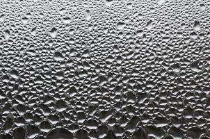 A photo of the glass surface of the window, covered with a multitude of droplets of various sizes. Background texture of a dense layer of condensate on glass