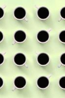 muchas tazas pequeñas de café blanco sobre fondo de textura de papel de color lima pastel de moda foto