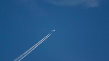 The plane flies high in the sky a white trail. A white trace of condensation behind a flying airplane. The condensation trail of the plane is high in the sky. video