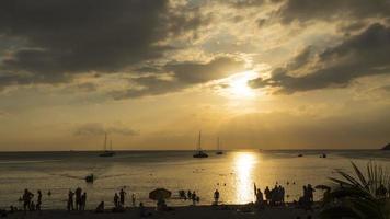 Malerische Meereslandschaft im Zeitraffer auf der Insel Phuket in der Abenddämmerung mit Booten, Yachten und Menschen am Strand und Surfen im Wasser video